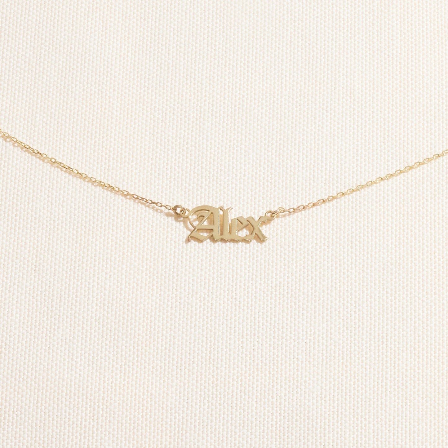 Gold 'Alex' necklace on a light beige background