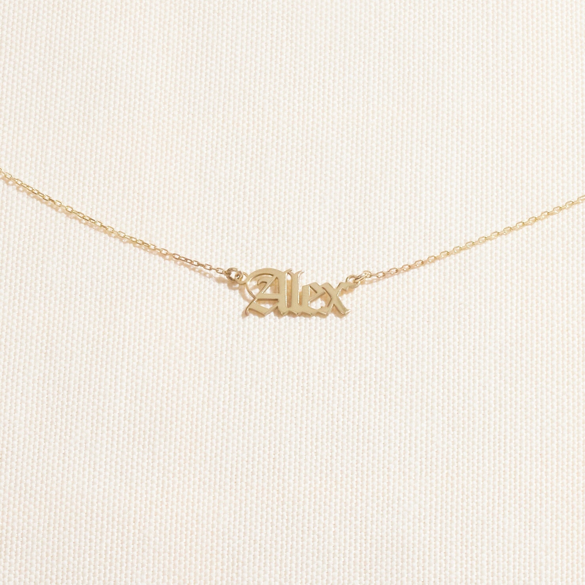 Gold 'Alex' necklace on a light beige background