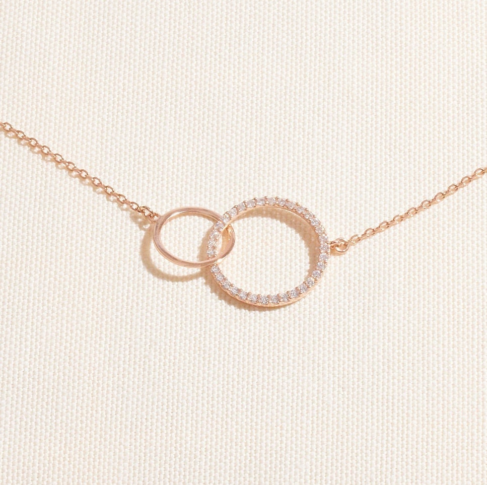 Rose gold necklace with interlocking rings on a light beige background
