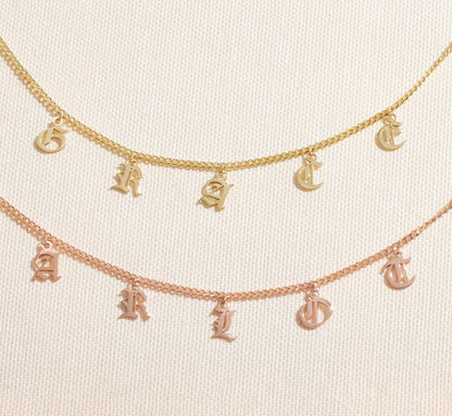 Personalized name necklace featuring Gothic dangle letters in gold and rose gold curb chain design.