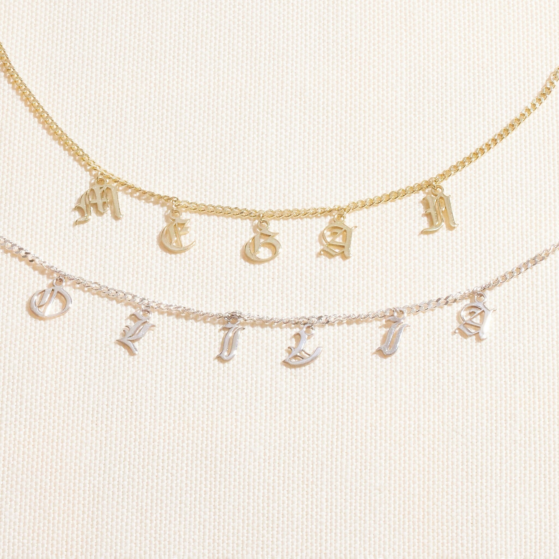 Personalized name necklace featuring Gothic Old English design with Dangle letters in gold and silver chains.