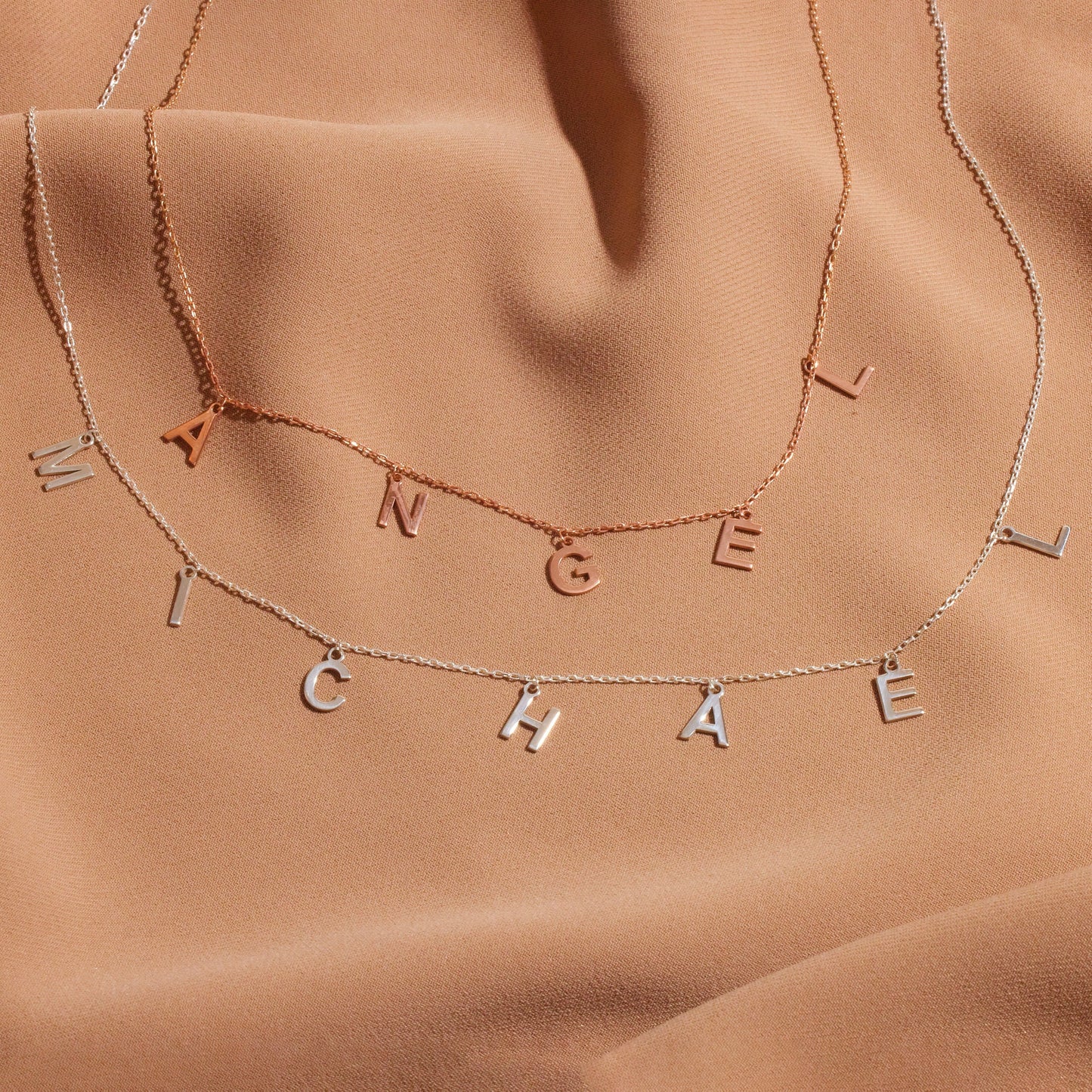 Necklaces with engraved names on a brown fabric background