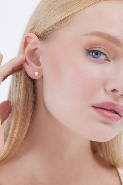 Close-up of a woman wearing pearl earrings with text 'SHIPS NEXT DAY' on a neutral background