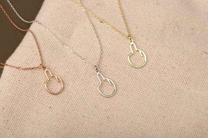 A close-up image of 3 tiny middle finger-shaped necklace in silver, gold and rose.