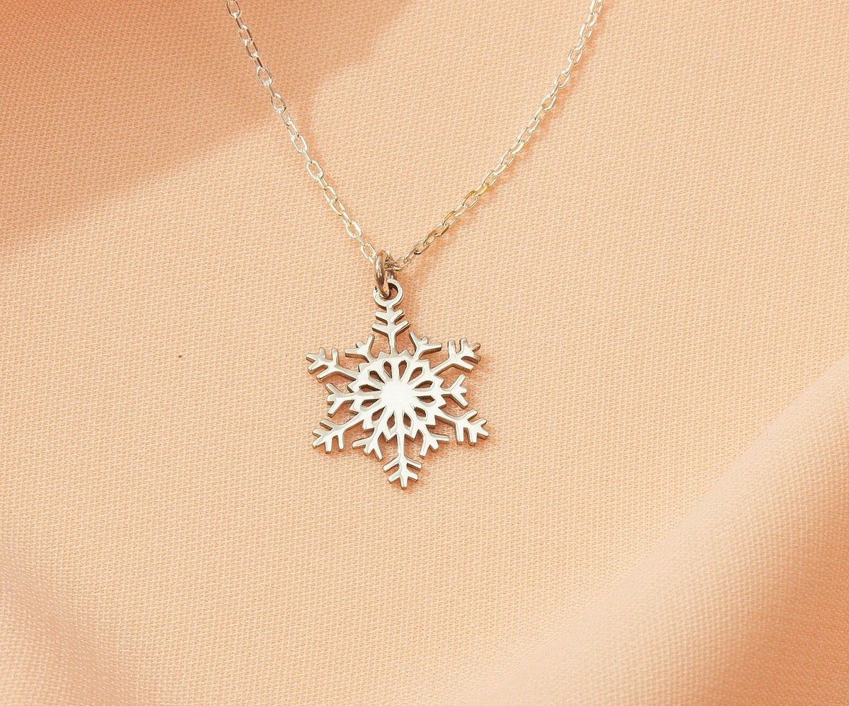 Silver snowflake necklace on a beige background