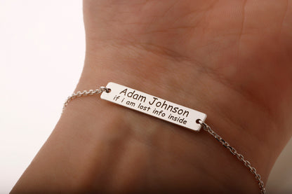 A personalized medical ID bracelet with silver chain and a rectangular silver charm featuring text.