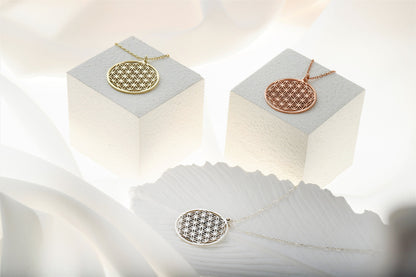 Two gold necklaces on white cubes with a soft white background