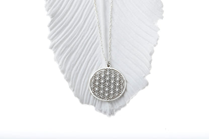 Silver necklace with a geometric pendant on a white fabric background