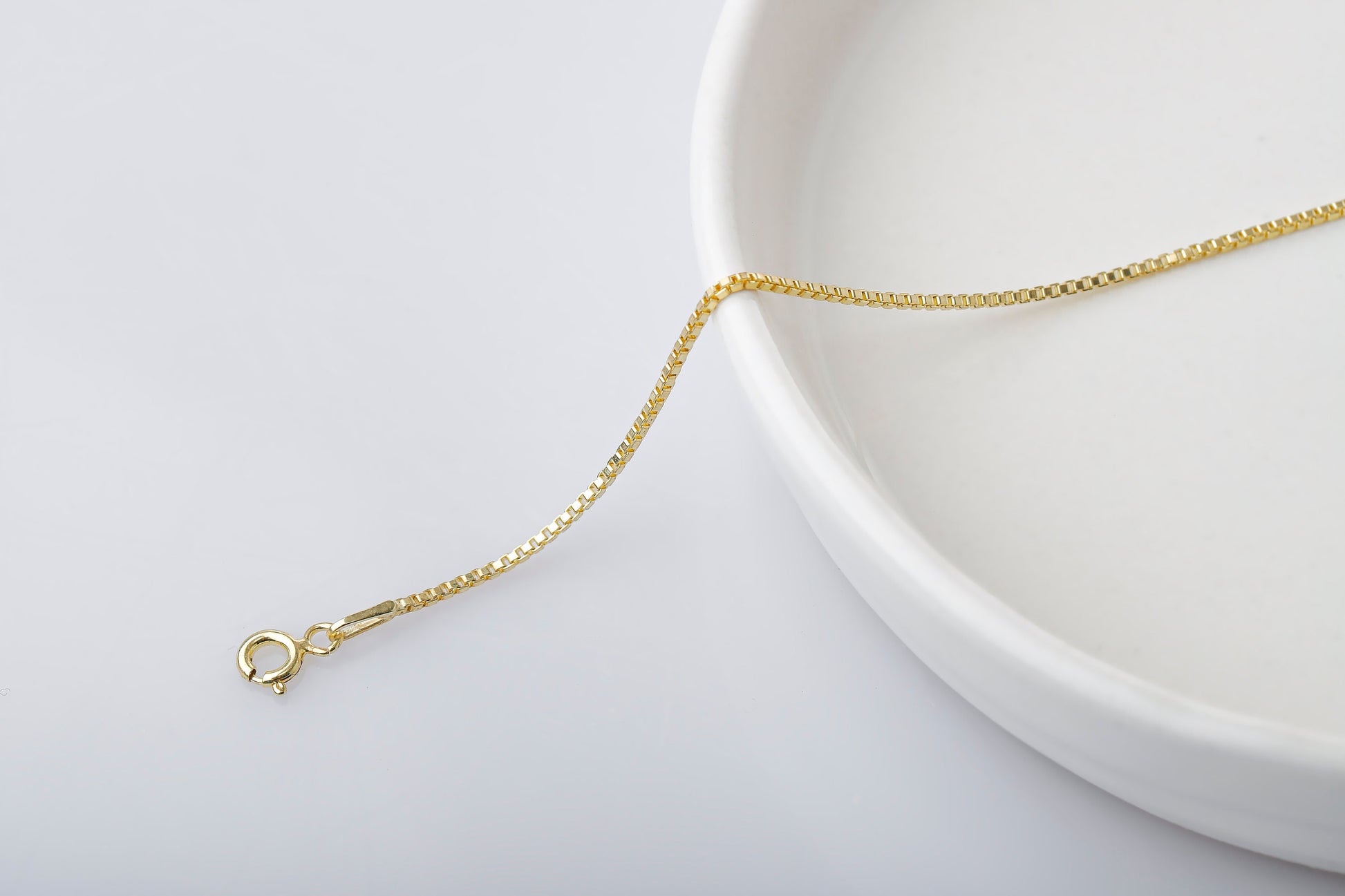 Gold necklace on a white plate with a white background