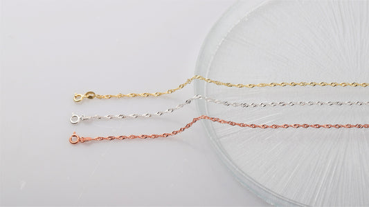 A close-up image of 3  Singapore chain necklaces in gold silver and rose on white background