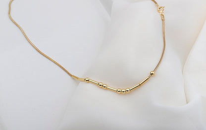 The image showcases a close-up of  a custom Morse code necklace with a personalized hidden message in Morse code. The necklace is gold-filled and has a snake chain design.