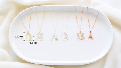 A gold-colored necklace with a pendant in the shape of a letter 'D' on a person's neck.