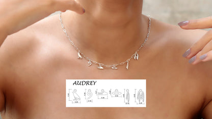 A close-up image of a silver personalized hieroglyphics necklace with a dainty waterproof link chain, shown around a person's neck.