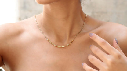 The image showcases a close-up of a person wearing a custom Morse code necklace with a personalized hidden message in Morse code. The necklace is gold-filled and has a snake chain design.