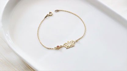 a dainty gold bracelet with a lotus flower design on white background.