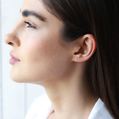 A close-up image of a person's ear wearing a small gold stud earring with the number '4'.