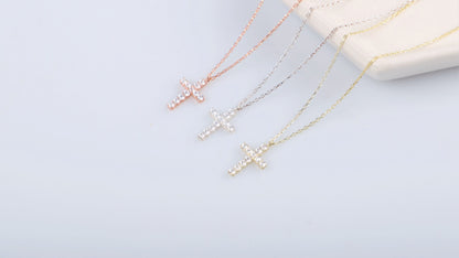 A close-up image of a person wearing a 14K gold diamond cross necklace with a delicate chain, displayed against a lacy black background.