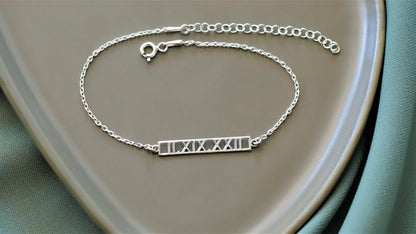 A sterling silver bar bracelet with Roman numerals engraved on it