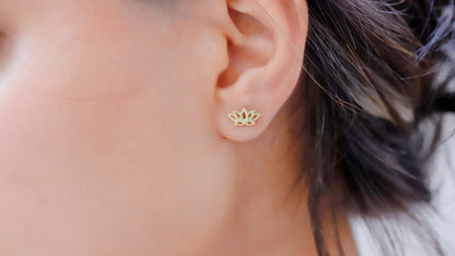 A person wearing a 14K gold dainty lotus flower stud earring in their ear.