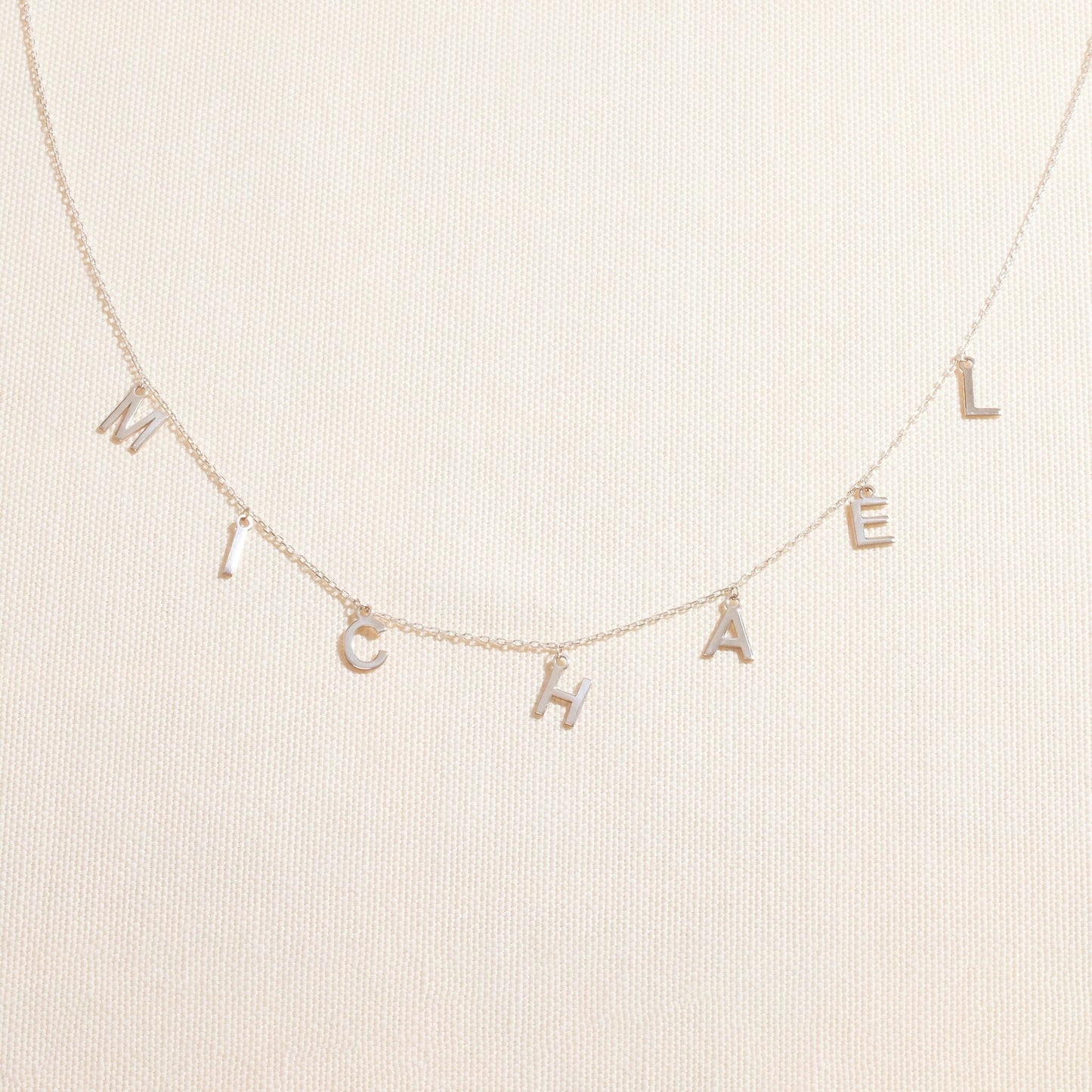Necklace with 'MICHAEL' letters on a beige background