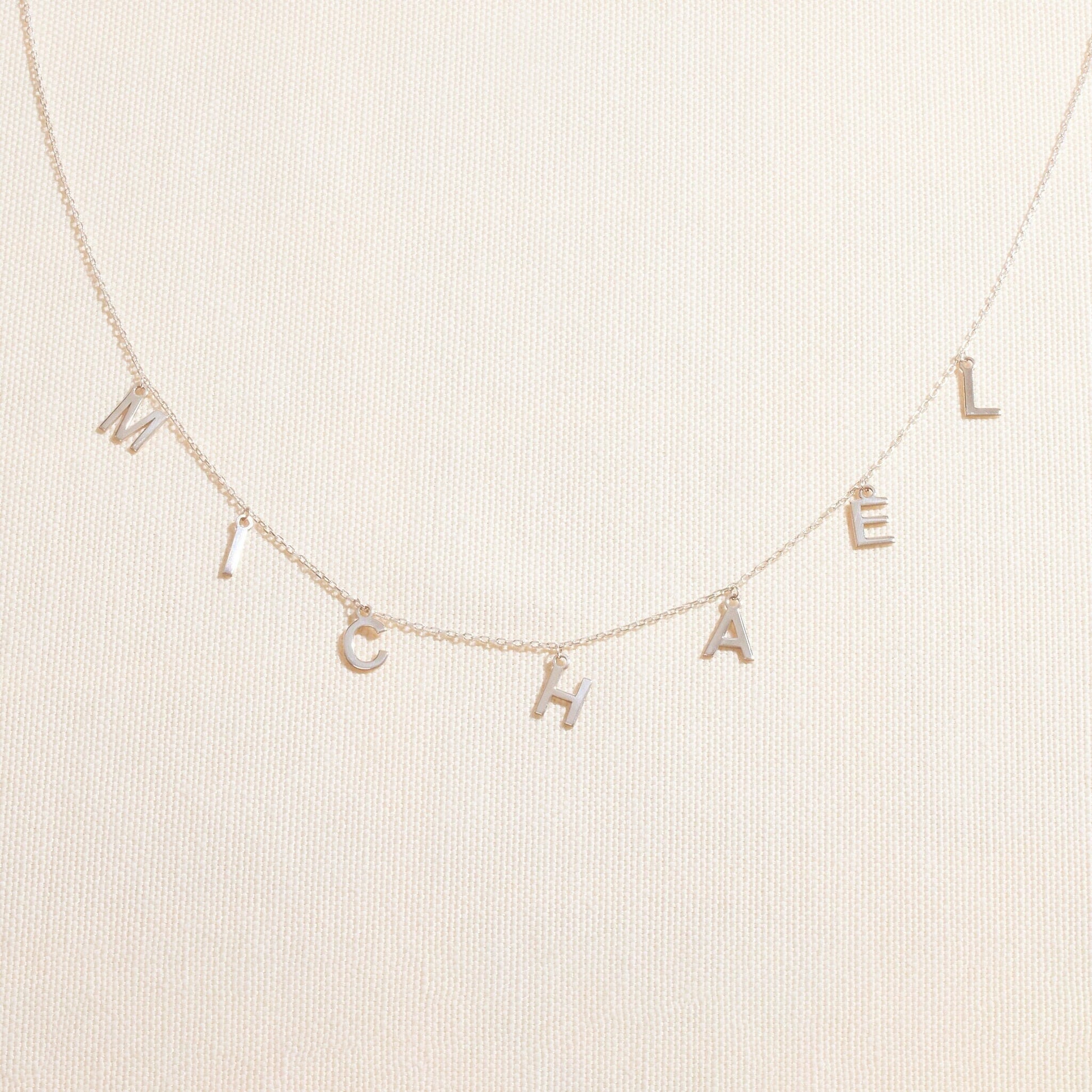 Necklace with 'MICHAEL' letters on a beige background