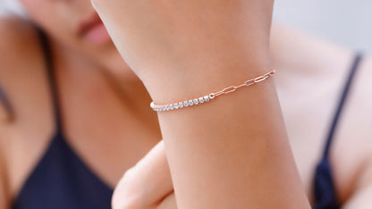 A close-up image of a person's wrist wearing a gold-colored half tennis half link chain bracelet with dainty CZ white diamonds.