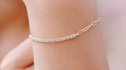 A close-up image of a person's wrist wearing a gold-colored half tennis half link chain bracelet with dainty CZ white diamonds.