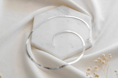Silver necklace on a soft beige fabric background