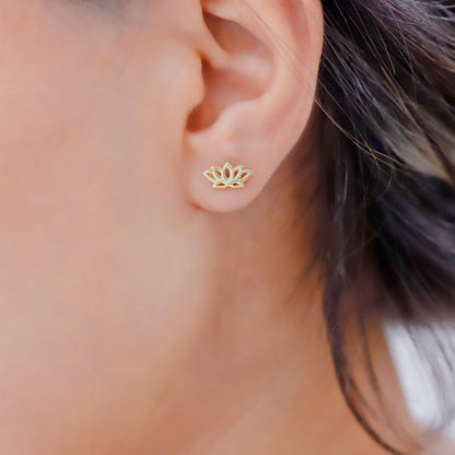 A person wearing a 14K gold dainty lotus flower stud earring in their ear.