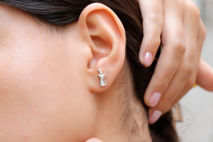 A close-up image of a person's ear wearing a sterling silver stud earring in the shape of a cat.