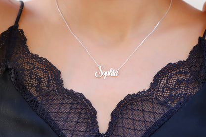 A close-up image of a silver name necklace on a person's neck, displaying the name 'Sophia' in cursive lettering.