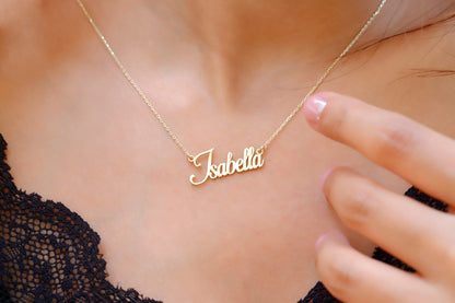 A close-up image of a gold name necklace on a person's neck, displaying the name 'Isabella' in cursive lettering.