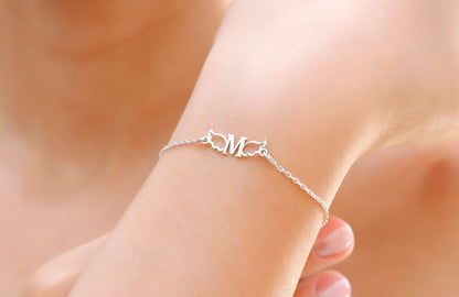 A close-up image of a person wearing a dainty silver bracelet with angel wing details on their wrist.