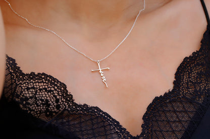 A close-up image of a woman wearing a personalized cross name necklace with the word 'Faith' inscribed on a gold faith cross pendant.