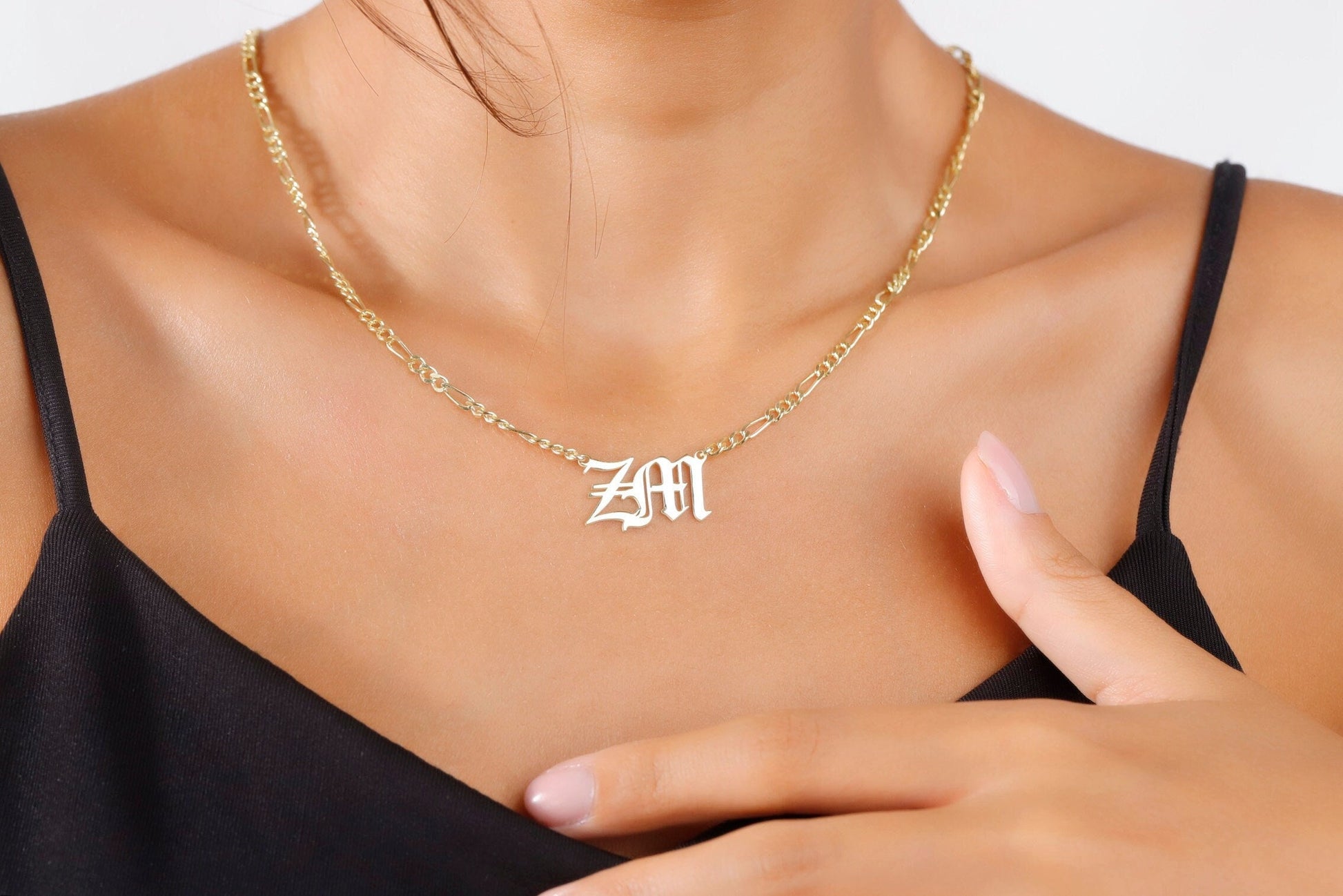 A top-down view of a gold-filled necklace with a Gothic font charm of the letters 'ZM', resting on a white surface. A product by SilverGoldandRose.com.
