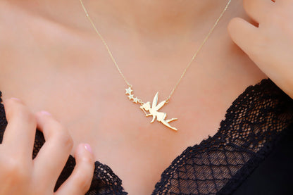A young girl wearing a gold-colored flying fairy necklace with intricate detailing.