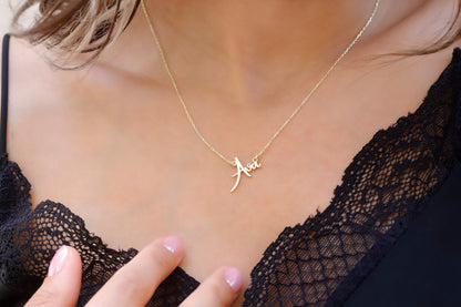 A person wearing a gold name necklace, with the name 'Jane' inscribed on a small, elegant pendant.