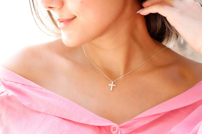 A close-up image of a woman wearing a 925 sterling silver, diamond cross necklace with a pendant cross on her neck.