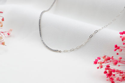 A close-up image of a silver tennis and paperclip chain necklace.