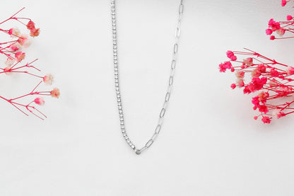 A close-up image of a silver tennis and paperclip chain necklace.