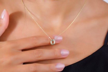 A close-up image of a woman wearing a gold-filled balloon necklace with a single letter 'O' pendant.