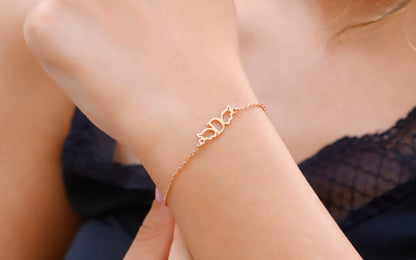 A close-up image of a person wearing a dainty silver bracelet with angel wing details on their wrist.