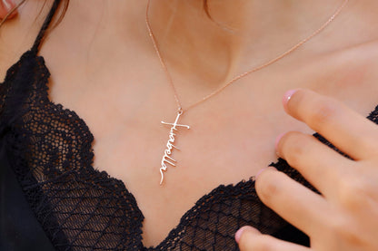 A close-up image of a woman wearing a personalized cross name necklace with the word 'Faith' inscribed on a gold faith cross pendant.