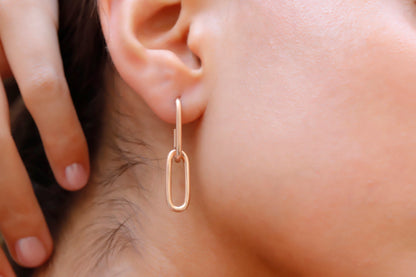 A woman wearing a silver dangle link chain chunky earring.