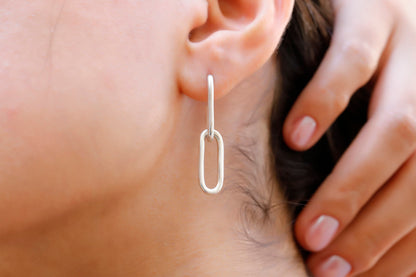 A woman wearing a silver dangle link chain chunky earring.