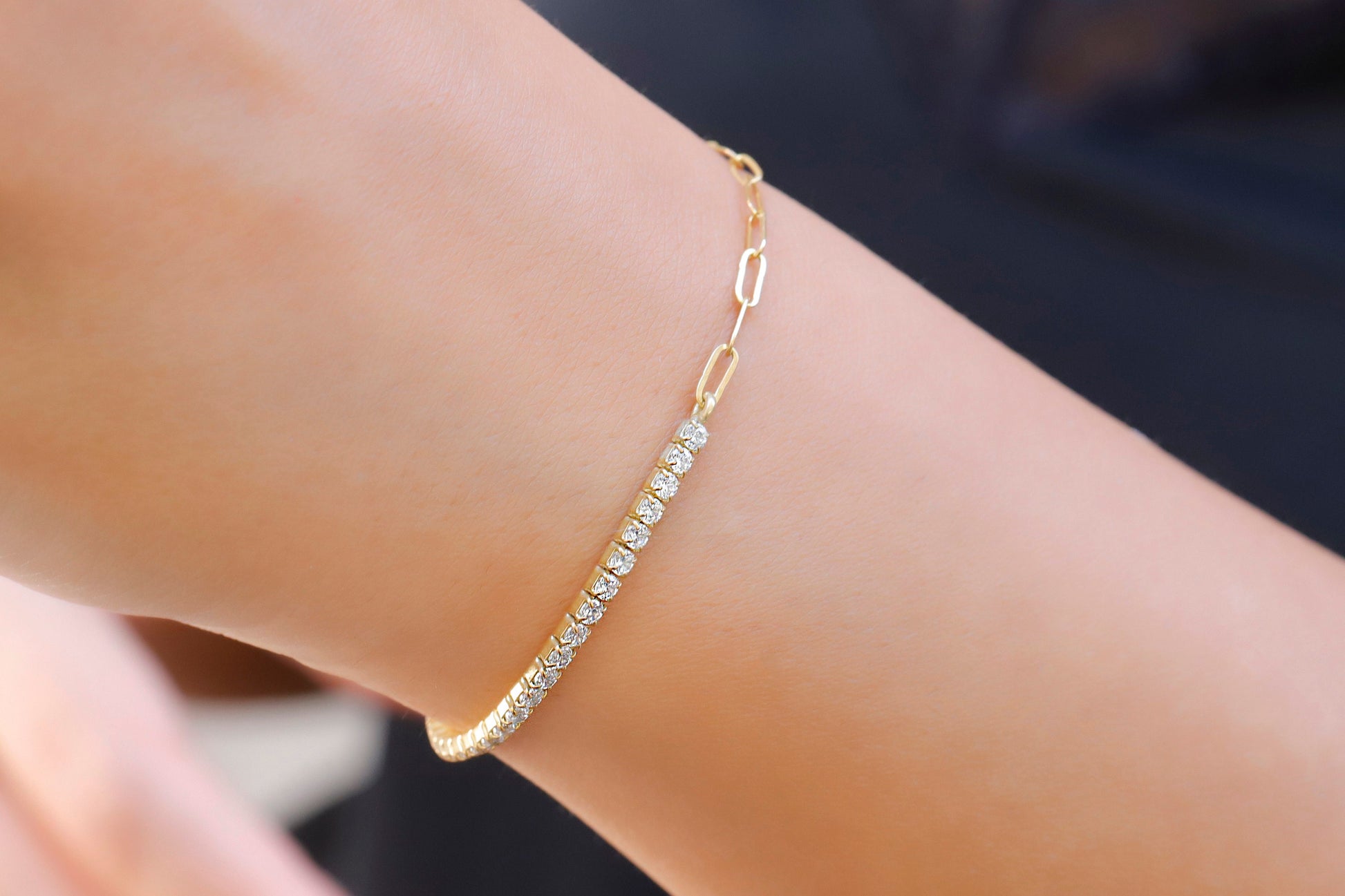 A close-up image of a tennis bracelet combined with a paperclip chain, displayed on a person's wrist.