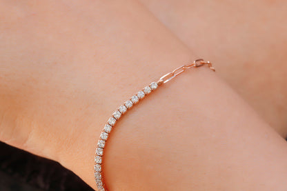 A close-up image of a tennis bracelet combined with a paperclip chain, displayed on a person's wrist.