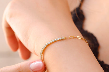 A close-up image of a tennis bracelet combined with a paperclip chain, displayed on a person's wrist.