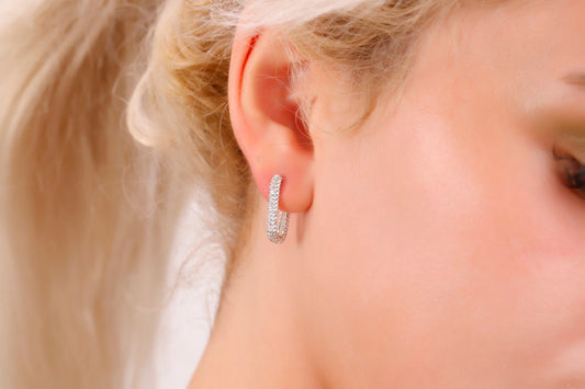 Close-up of an ear wearing a diamond earring with blonde hair.