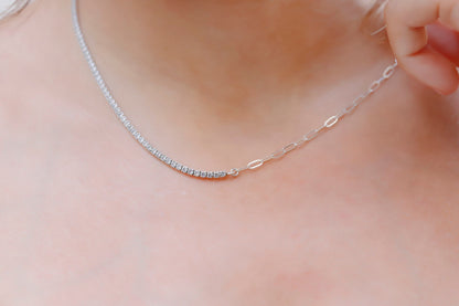 A close-up image of a silver tennis and paperclip chain necklace.
